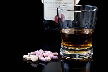 Verre d'alcool posé à côté de gélules de médicaments