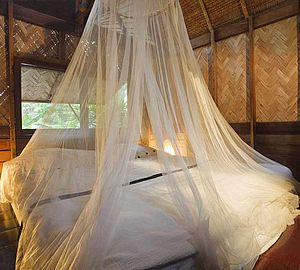 Chambre d'hôtel avec lit protégé par une moustiquaire
