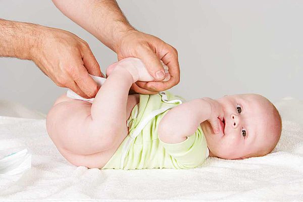 Papa passant une lingette sur les fesses de son bébé