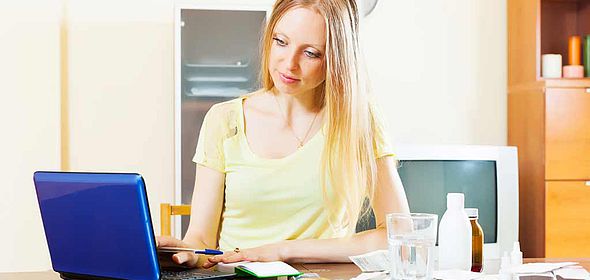 Femme devant son ordinateur et devant des médicaments