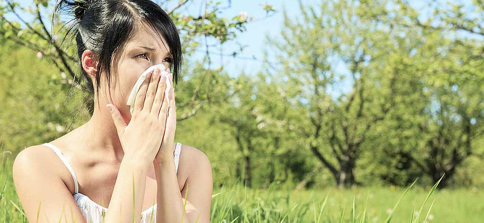 Femme se mouchant dans un champ de pollen à cause des allergies