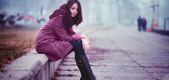Femme triste assise sur le bord d'un trottoir