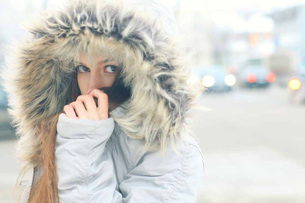 Femme se cachant dans la capuche de son manteau d'hiver