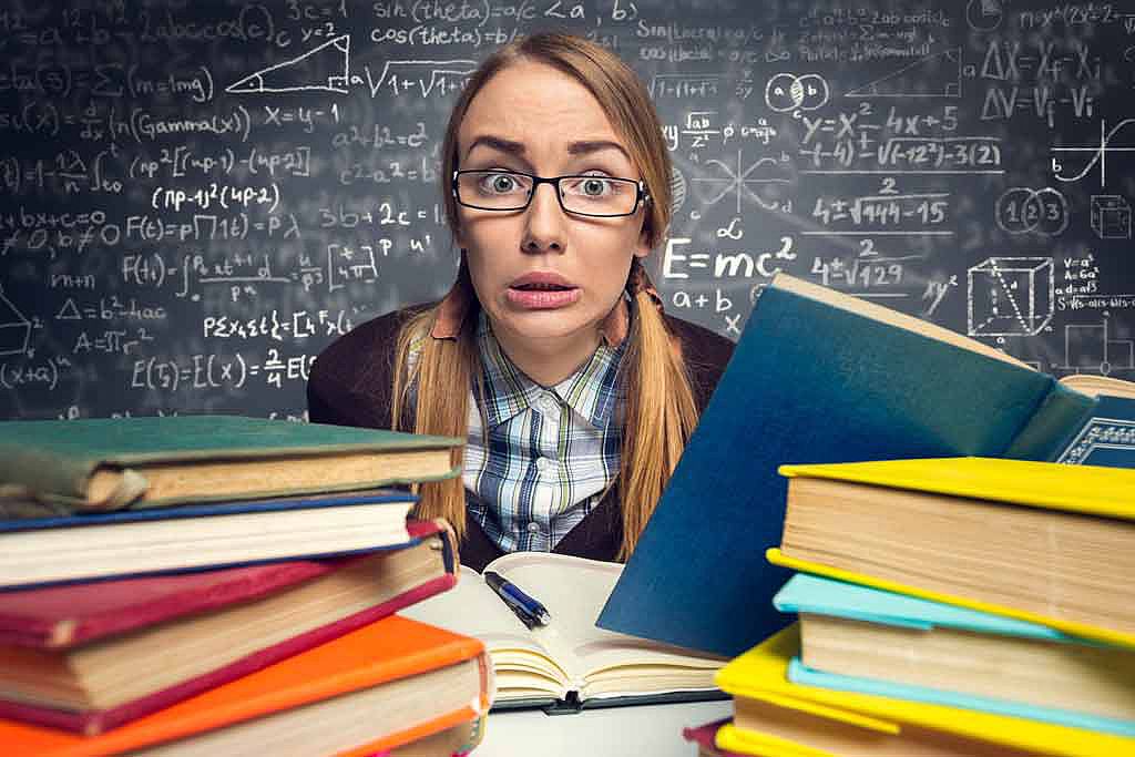 Femme stressée devant une pile de bouquins et un tableau noir