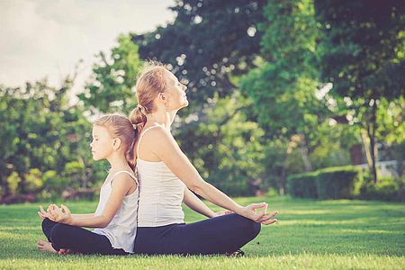 Femme se relaxant en posture de yoga avec sa fille