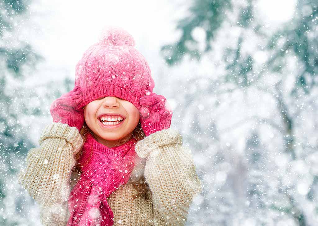Enfant enfilant un bonnet dans un décor neigeux