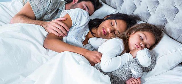 Famille dormant paisiblement dans un lit