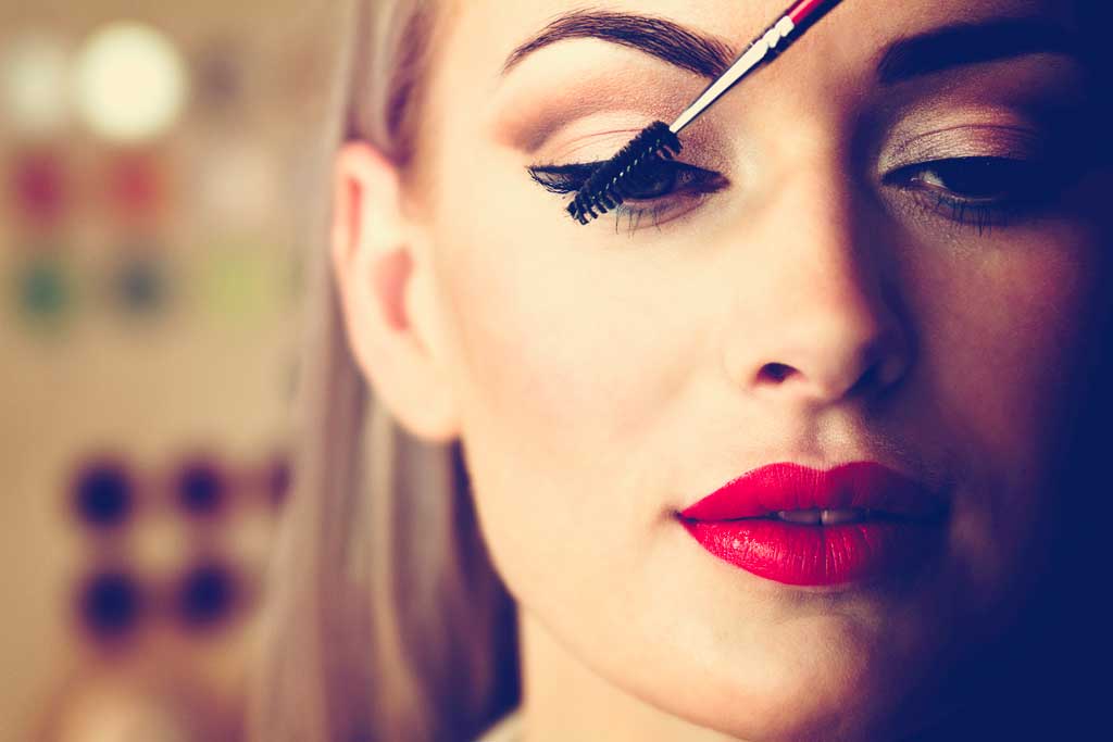 Femme avec rouge à lèvre se maquillant les yeux